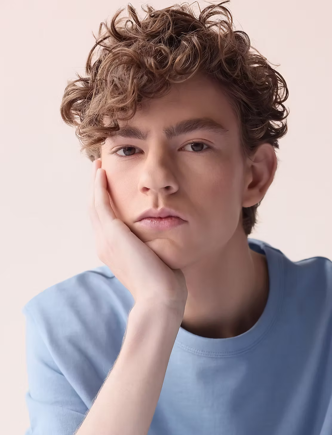 A young neurodivergent person resting their chin on their hand