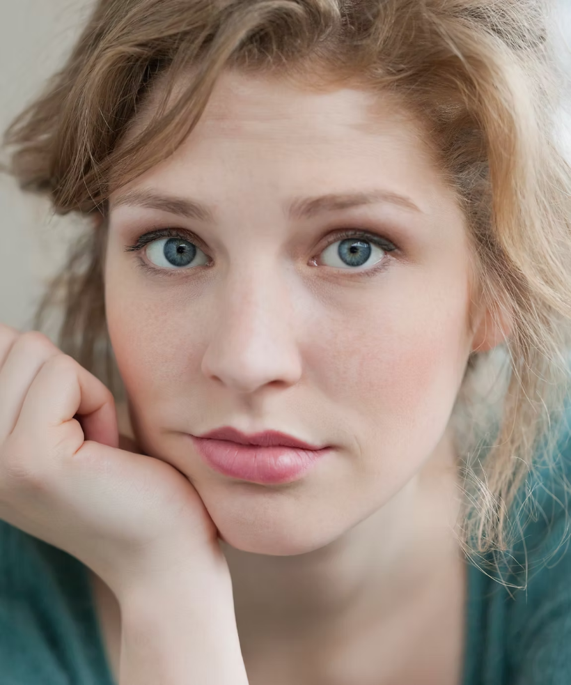 A woman resting her chin on her hand, looking thoughtful